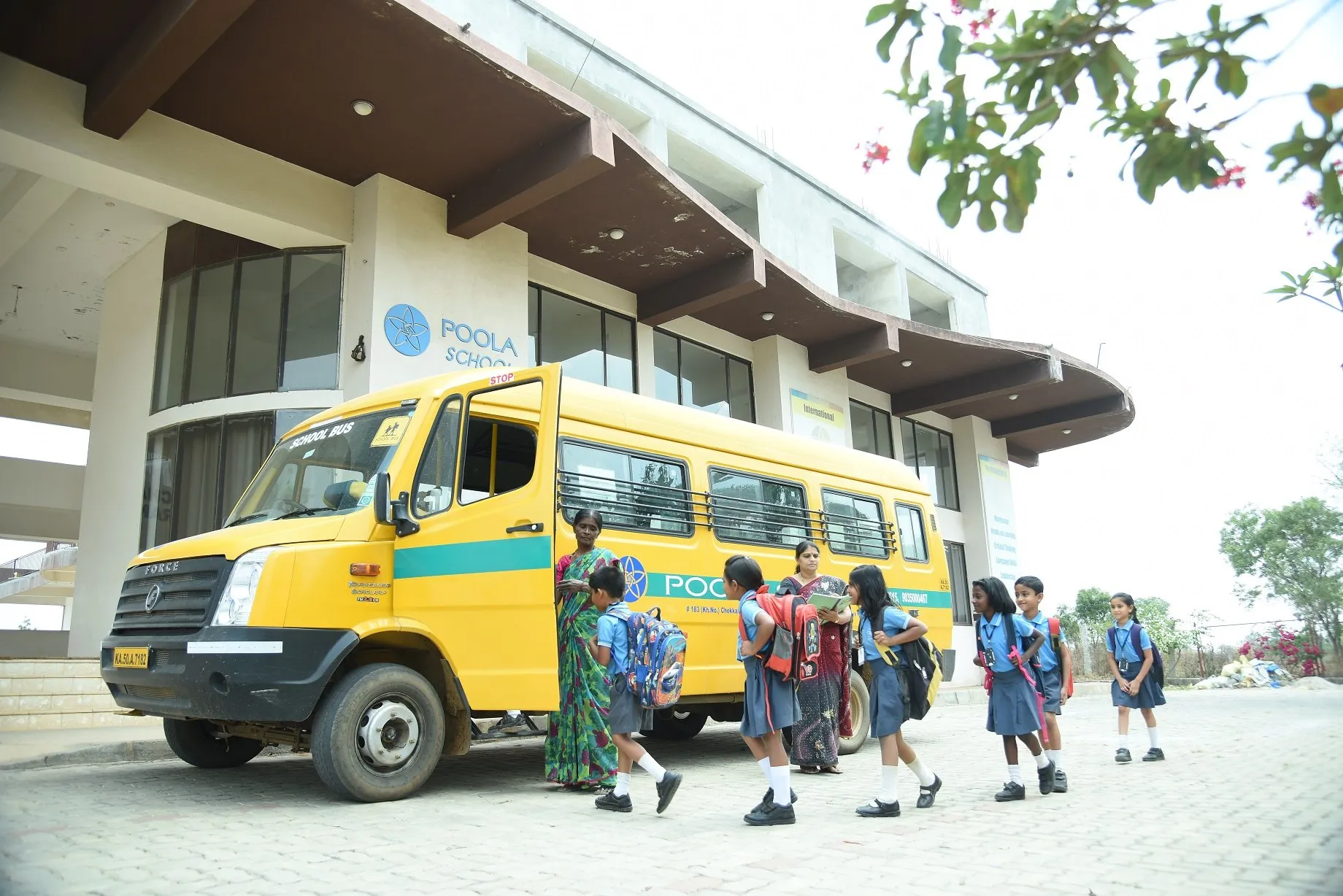 Children walking up to the Poola School entrance with the school bus behind them